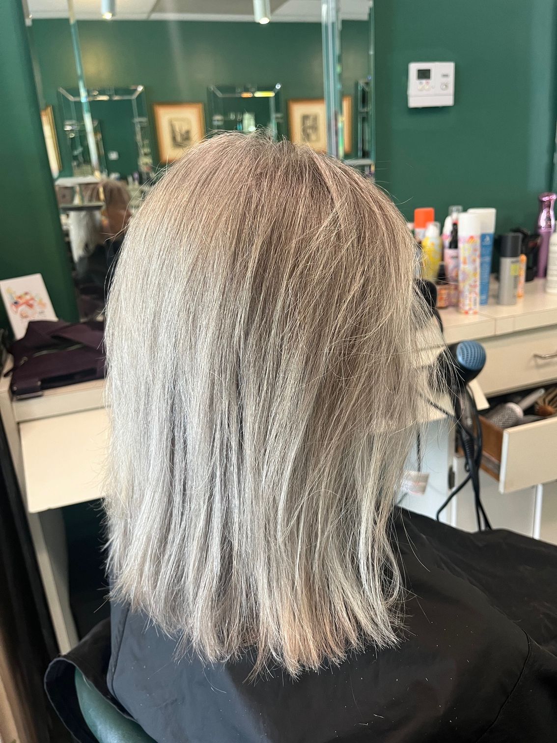 Person with hair covered in light-colored product, seated in a hair salon.