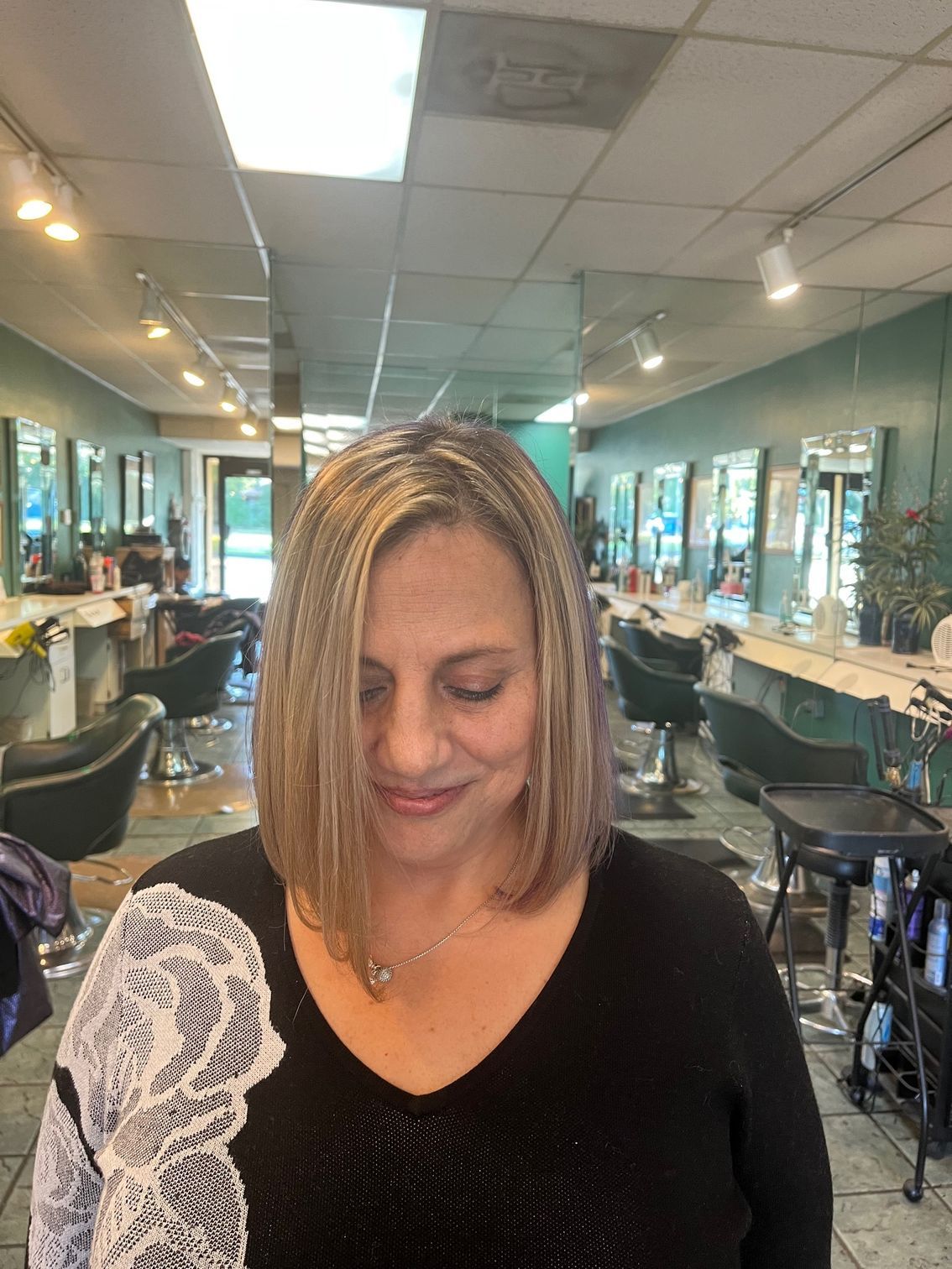 Woman getting her hair cut at a salon; stylist holds hair with one hand and scissors with the other.