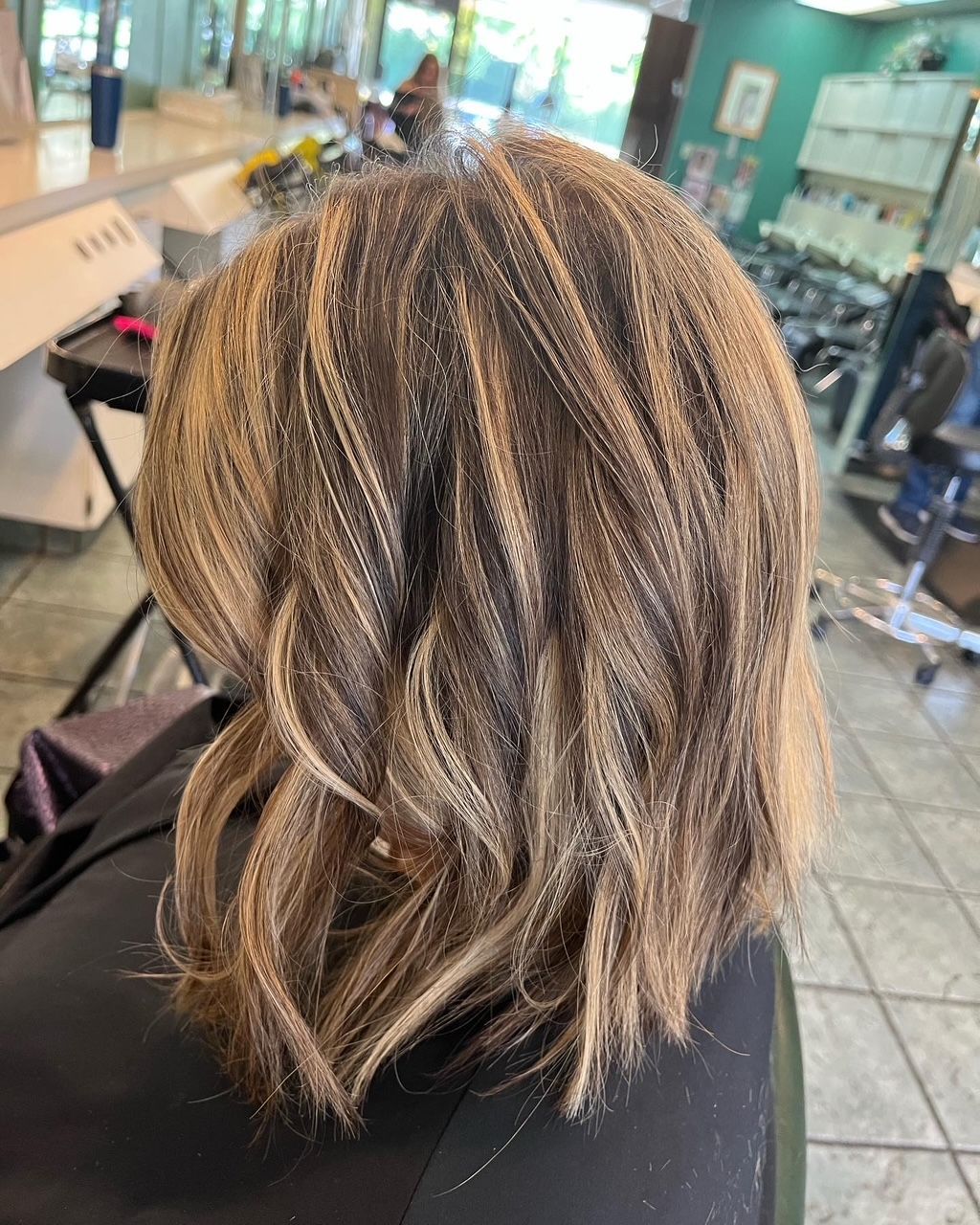 Close-up of hair with crimped texture, shades of brown and blonde, in a salon setting.