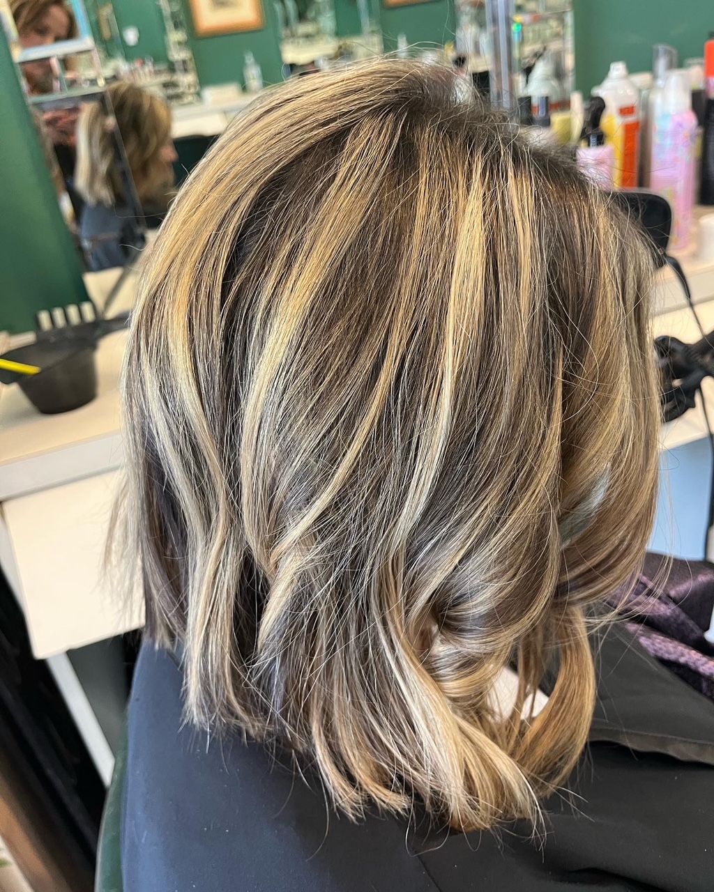 Woman's highlighted bob hairstyle. Brown, blonde, and tan layers with wavy texture in salon.
