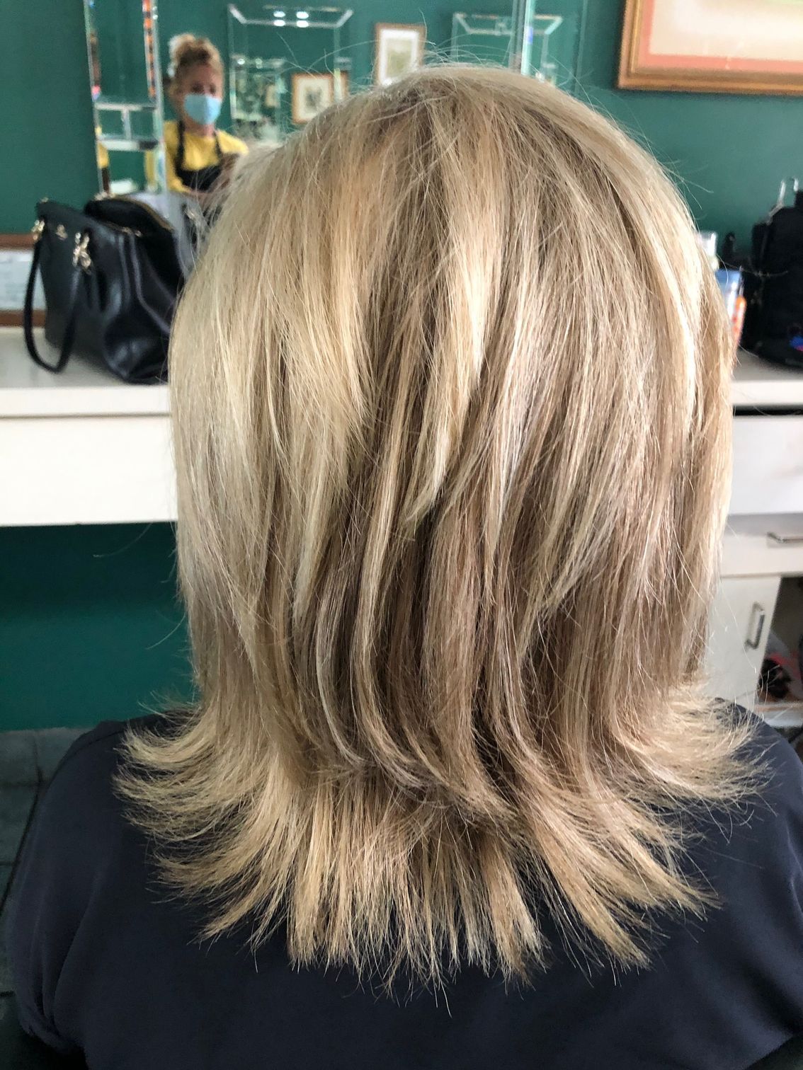 Blonde layered hair in a salon setting, styled in a bob with visible highlights.