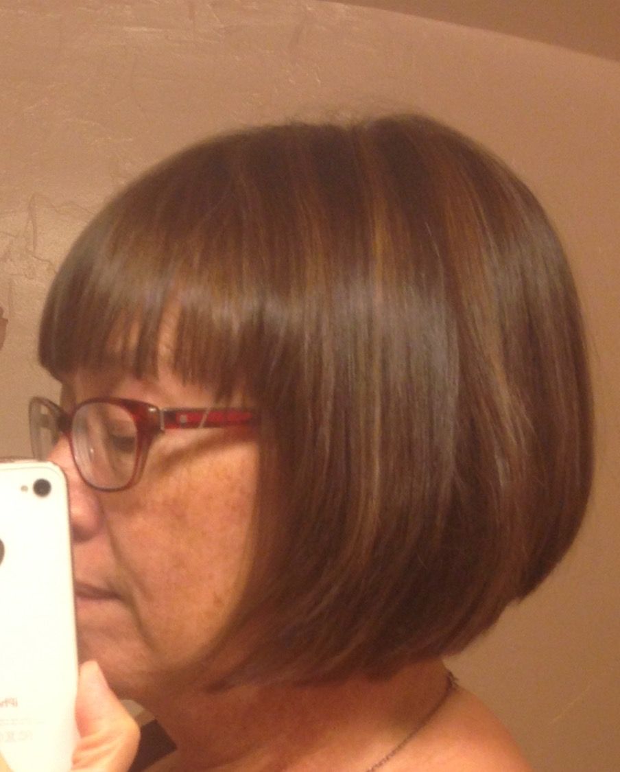 Woman with brown bob haircut, wearing glasses, holding a phone.