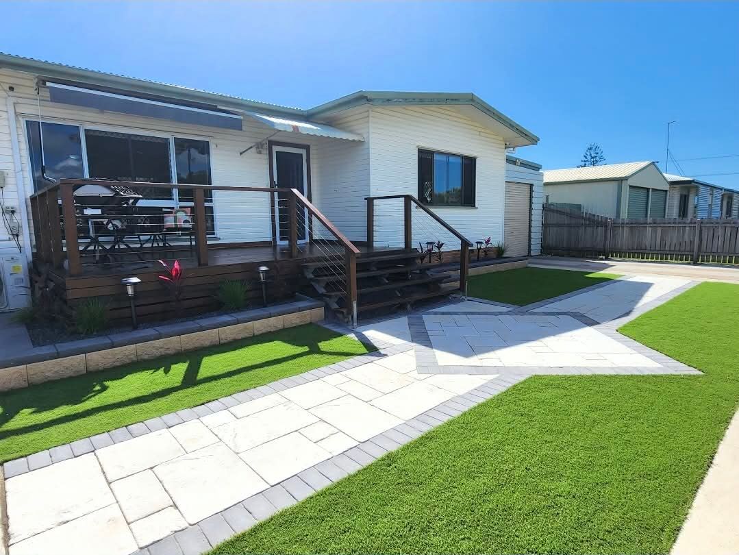White House With Brown Deck, Pathway, and Green Lawn Under a Blue Sky — On The Mark Landscaping in Branyan, QLD