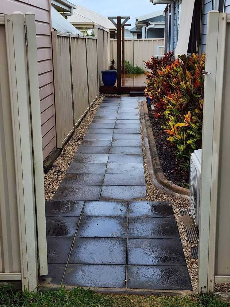 Narrow Outdoor Walkway Paved With Dark Tiles, Flanked by Fences and Garden Beds — On The Mark Landscaping in Branyan, QLD
