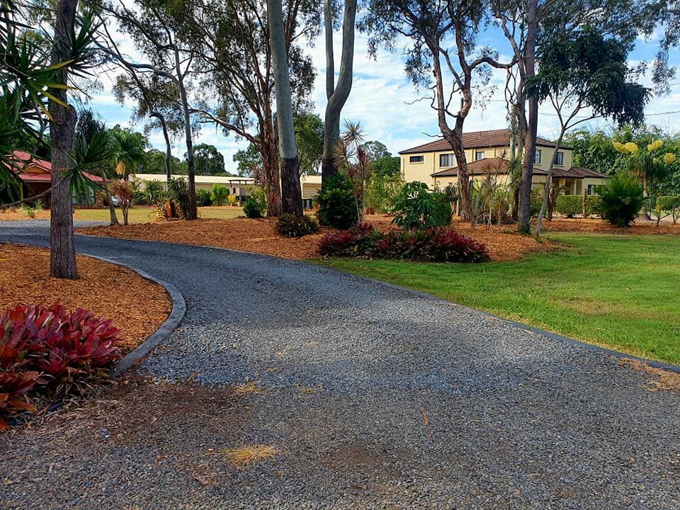 Gravel Driveway Curves Toward a Large House, Surrounded by Trees and Gardens — On The Mark Landscaping in Bargara, QLD