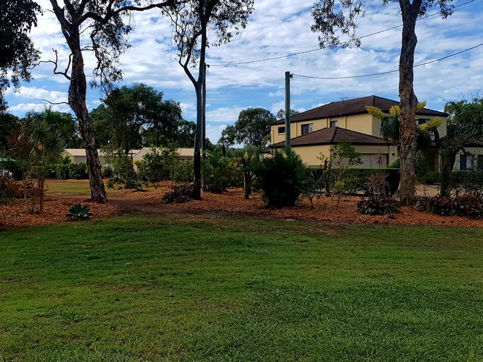Green Grass With Trees, Shrubs, and a Beige Two-story House — On The Mark Landscaping in Burnett Heads, QLD