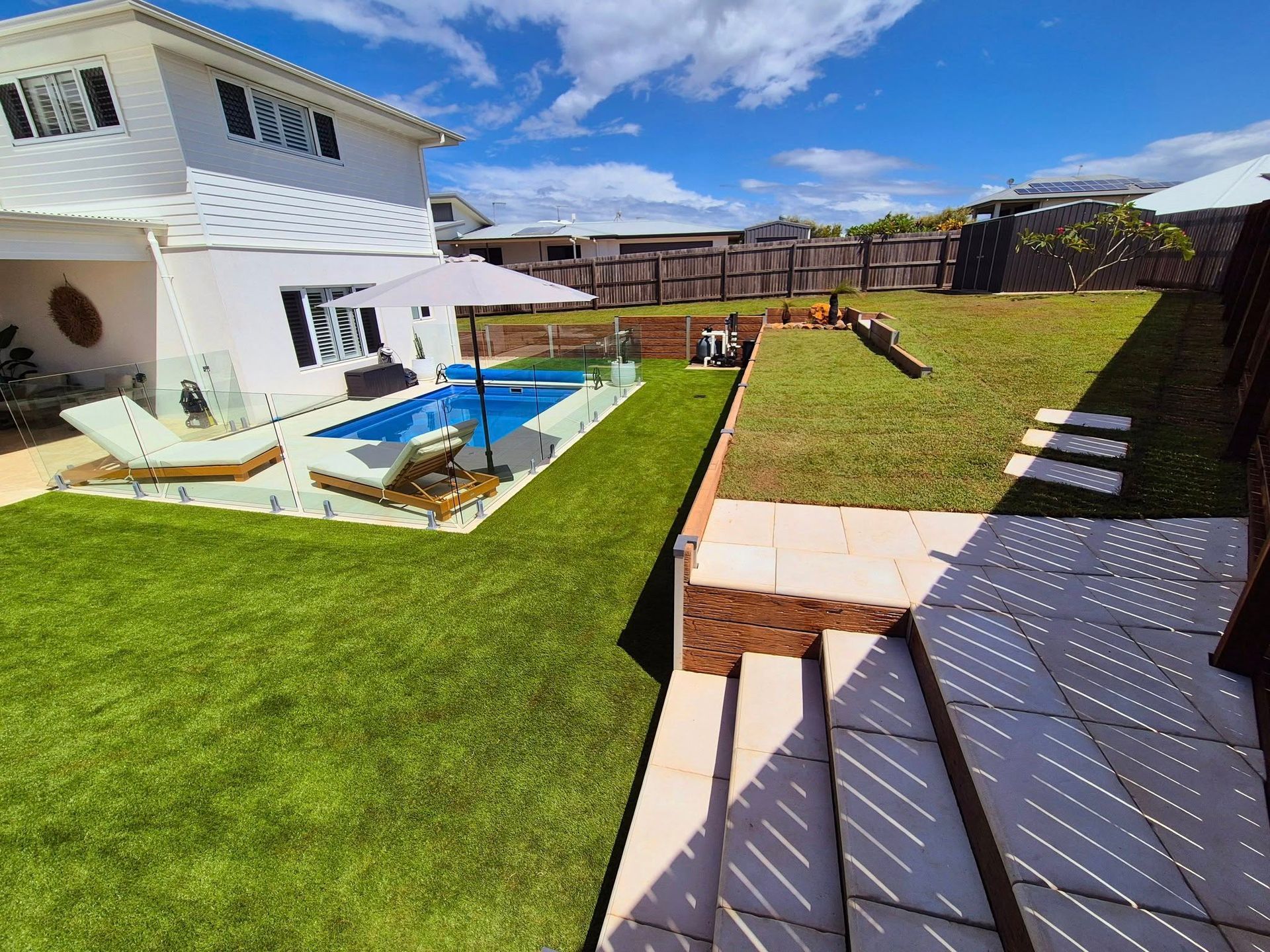 Backyard With a Pool, Lawn, and Multi-level Patio Under a Blue Sky — On The Mark Landscaping in Branyan, QLD