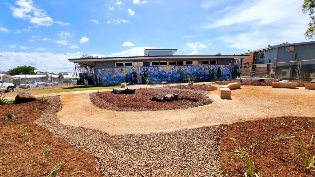 Exterior of a School With a Garden, Featuring a Mural, Soil, and Wood Blocks — On The Mark Landscaping in Elliot Heads, QLD