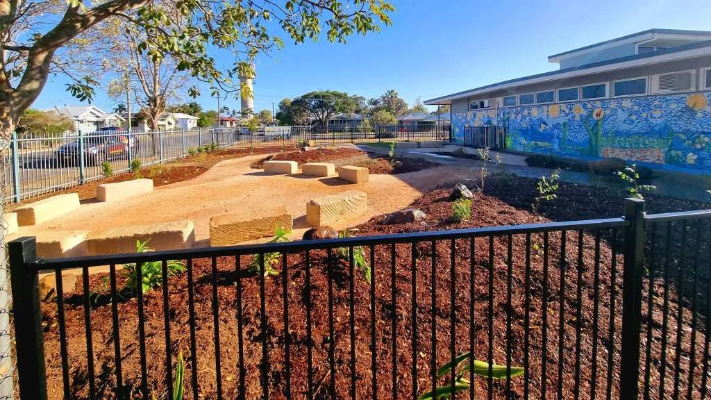 Playground With Wooden Blocks, Mulch, and Building With Mural — On The Mark Landscaping in Burnett Heads, QLD