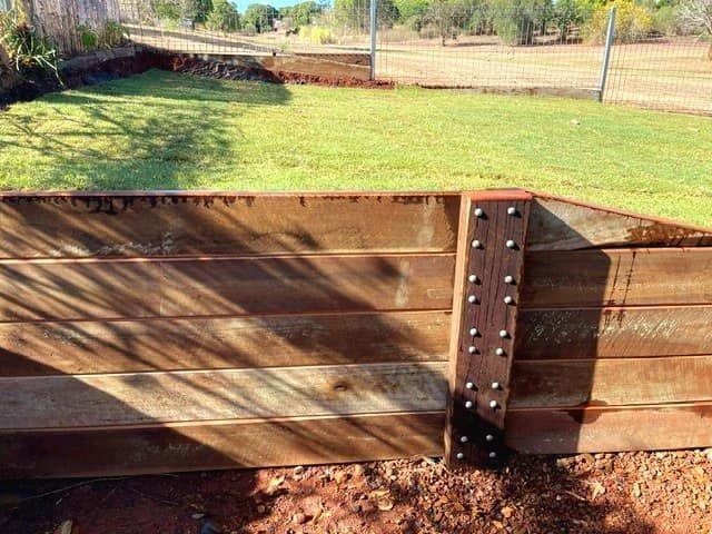 Wooden Retaining Wall With Brown Boards and a Grassy Yard — On The Mark Landscaping in Branyan, QLD