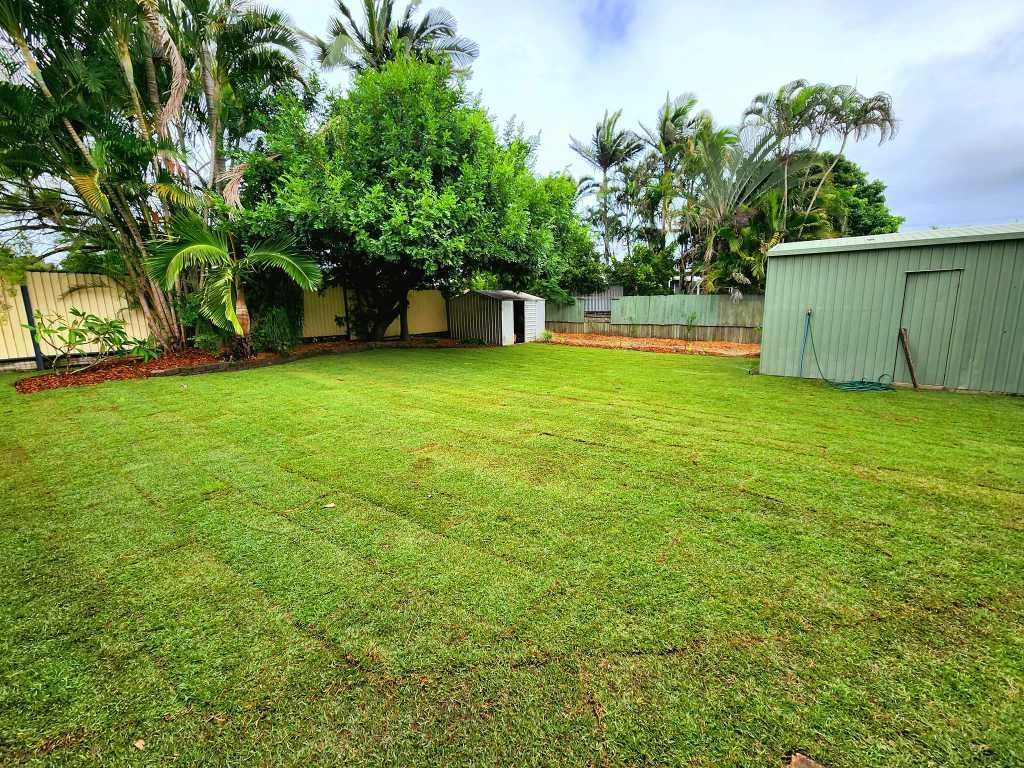 Grassy Backyard With Green Shed, Fence, and Trees Under Cloudy Sky — On The Mark Landscaping in Branyan, QLD