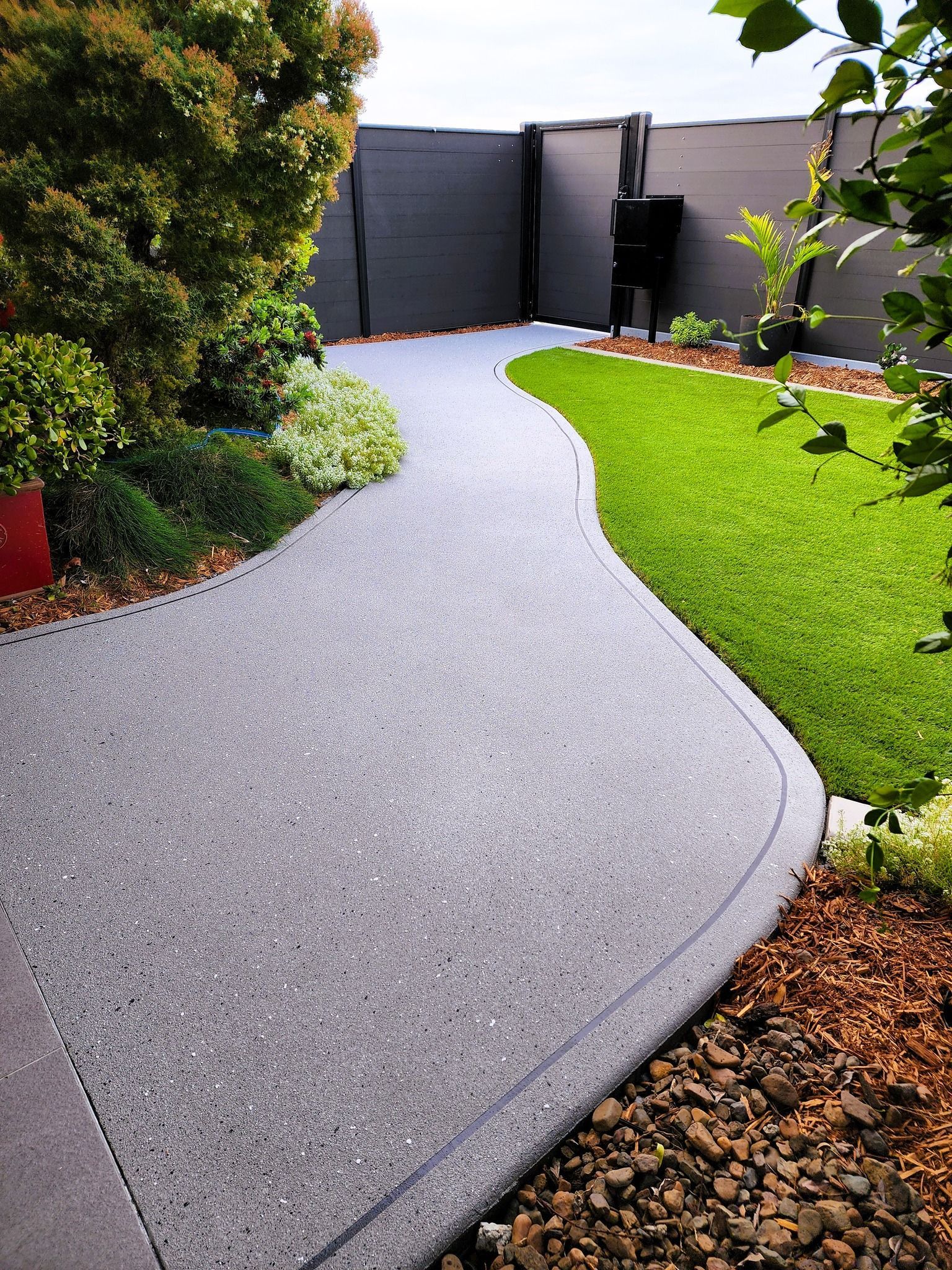 Curving Gray Concrete Path Through Landscaped Backyard — On The Mark Landscaping in Branyan, QLD