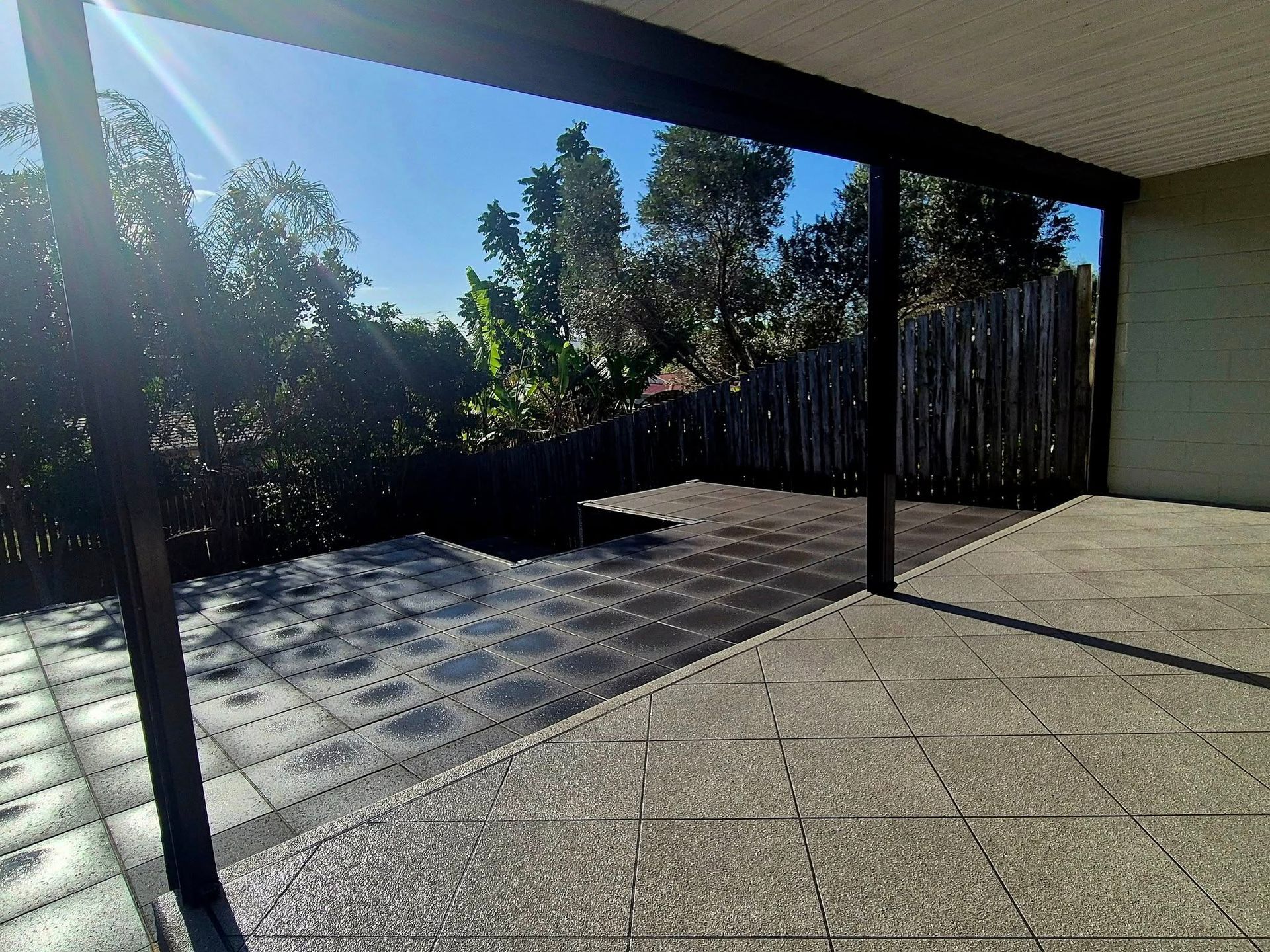 Patio With Dark Gray Tiles, Overlooking a Garden and Blue Sky — On The Mark Landscaping in Branyan, QLD