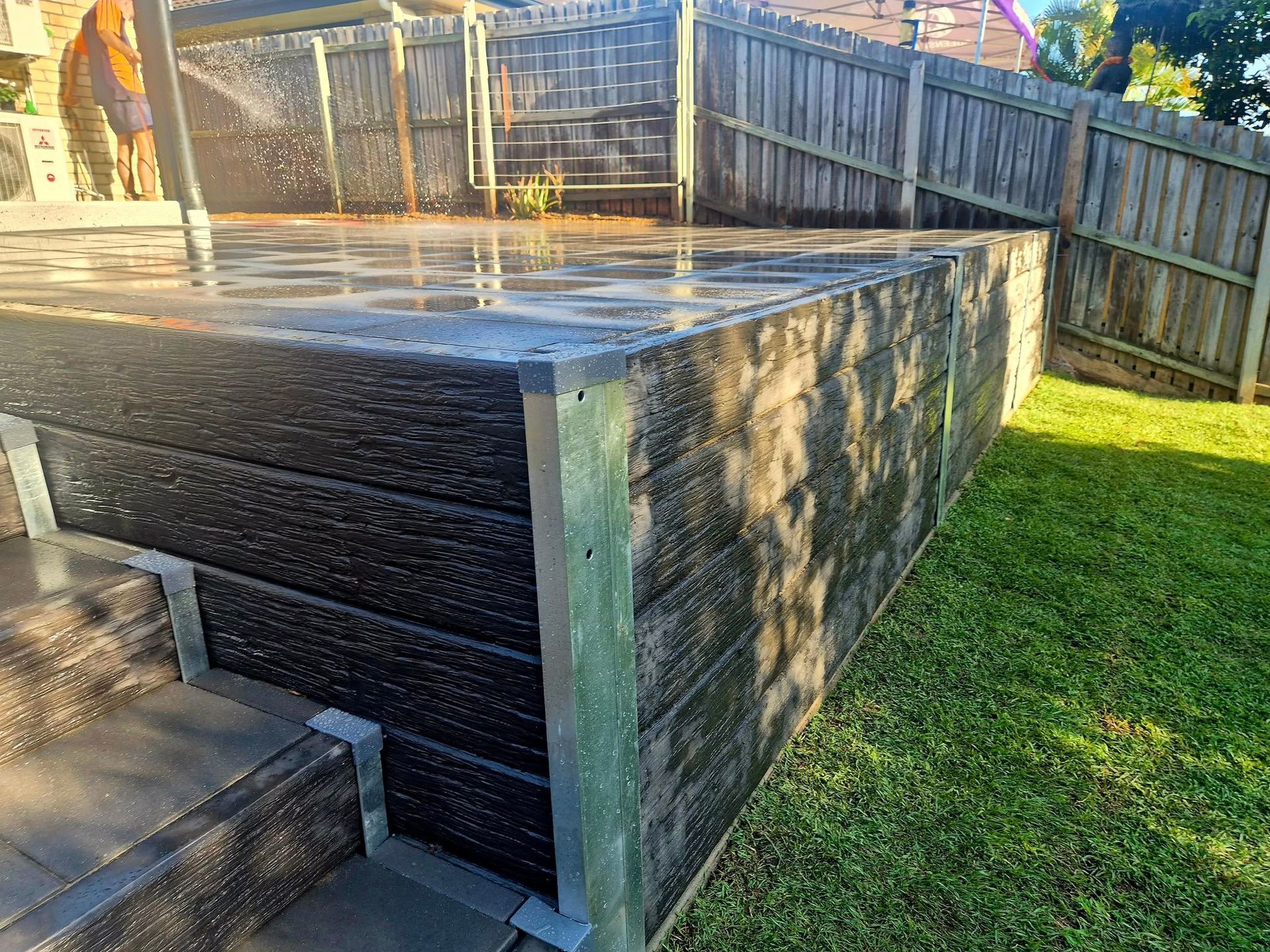 Raised Black Wooden Deck With Metal Trim, Adjacent to a Wooden Fence — On The Mark Landscaping in Branyan, QLD