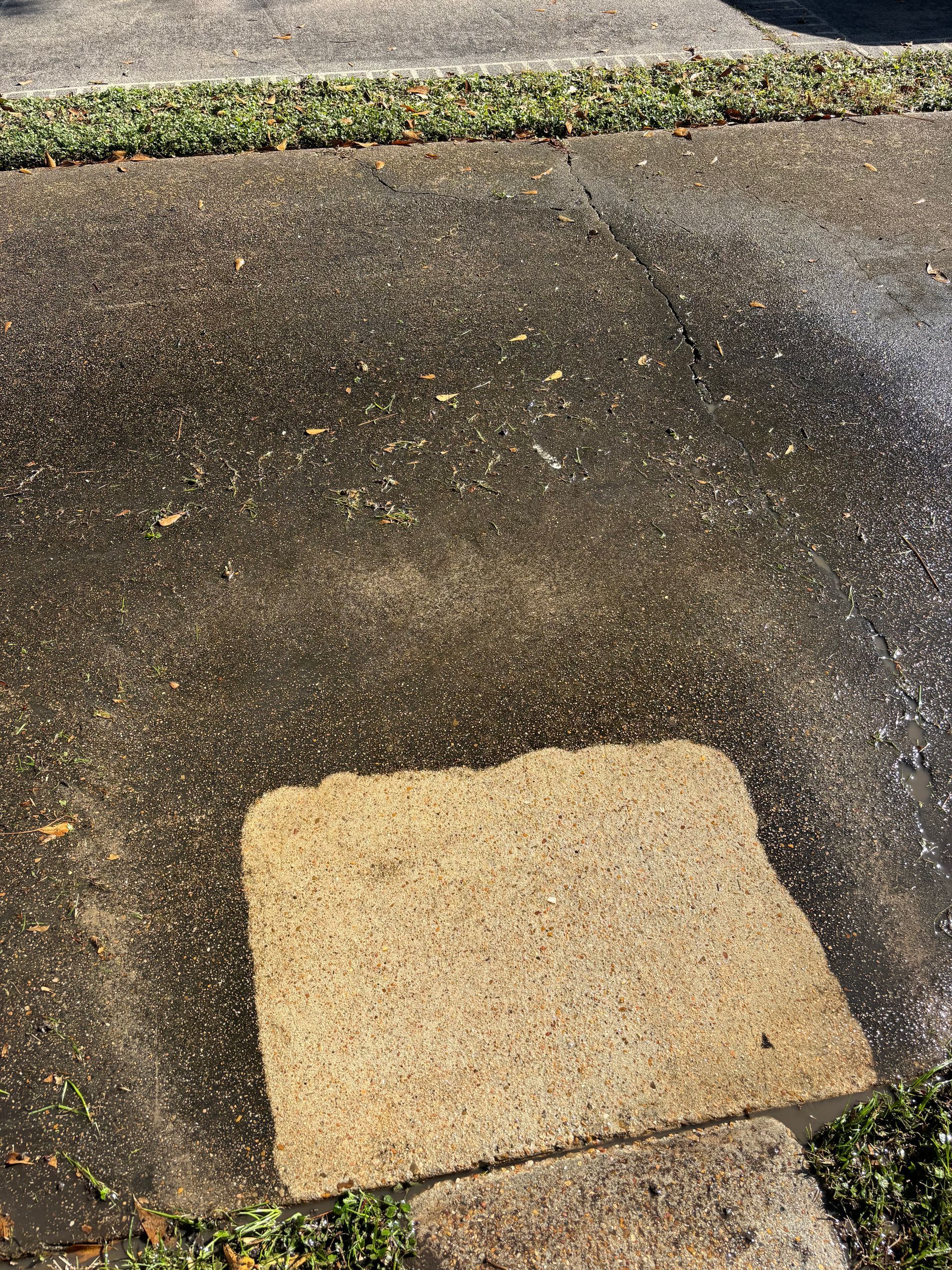 A person is using a high pressure washer to clean a brick walkway.