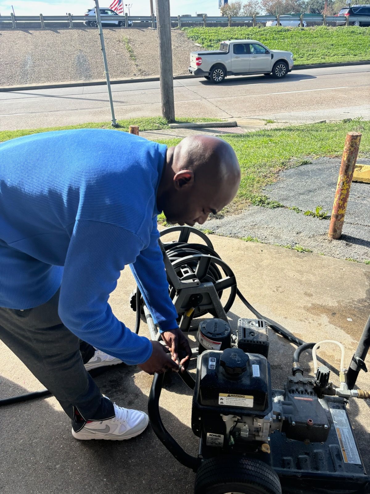 A yellow high pressure washer is cleaning a brick sidewalk.