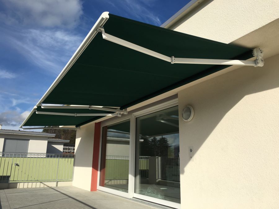 Eine grüne Markise befindet sich an der Seite eines Gebäudes