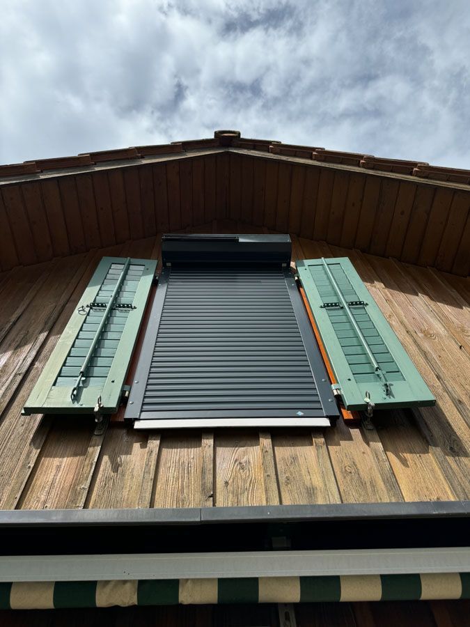 Ein Fenster mit grünen Fensterläden an einem Holzgebäude