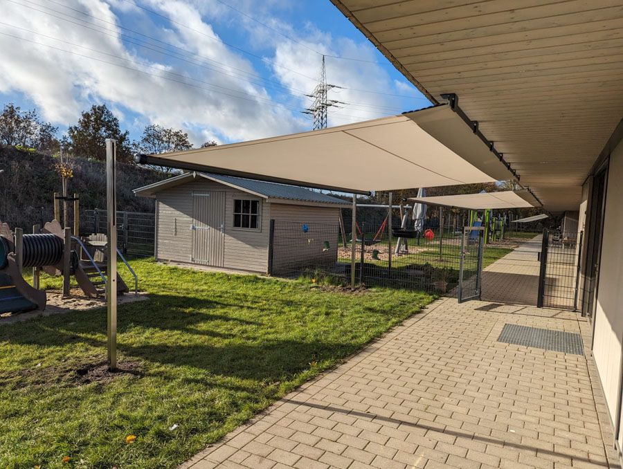 Eine Terrasse mit Überdachung und einem Spielplatz im Hintergrund.