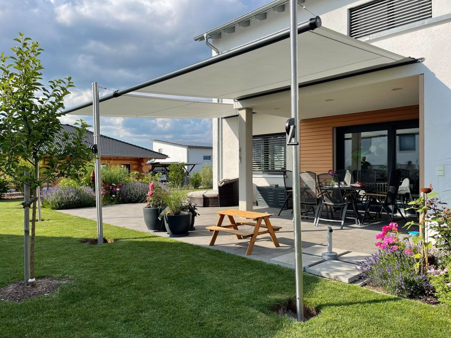 Im Hinterhof eines Hauses steht unter einem Baldachin ein Picknicktisch.