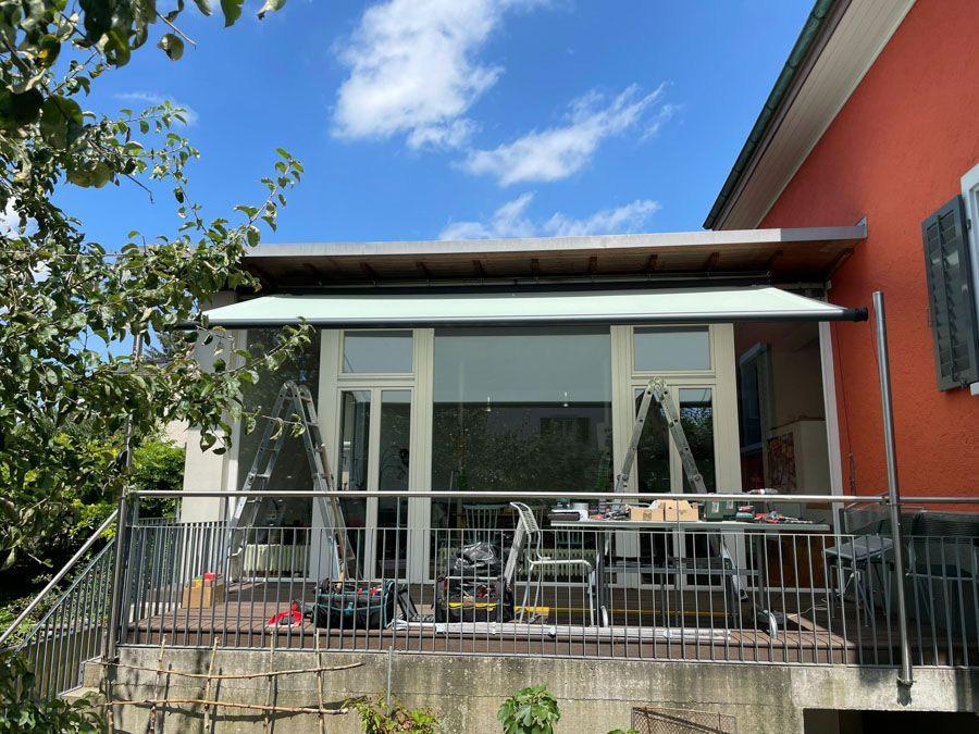 Die Rückseite eines Hauses mit Balkon und Markise.