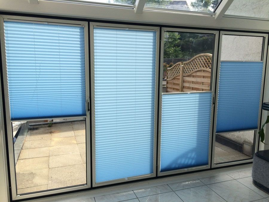 Ein Zimmer mit blauen Jalousien an einer Glasschiebetür