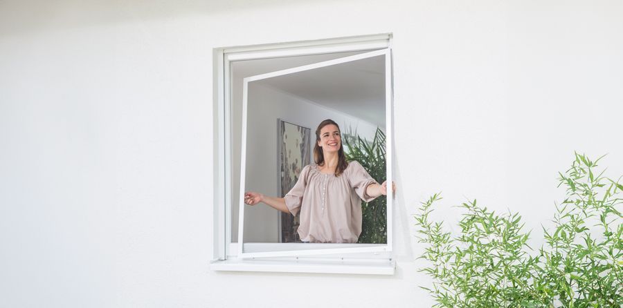 Eine Frau schaut aus einem Fenster mit Moskitonetz.