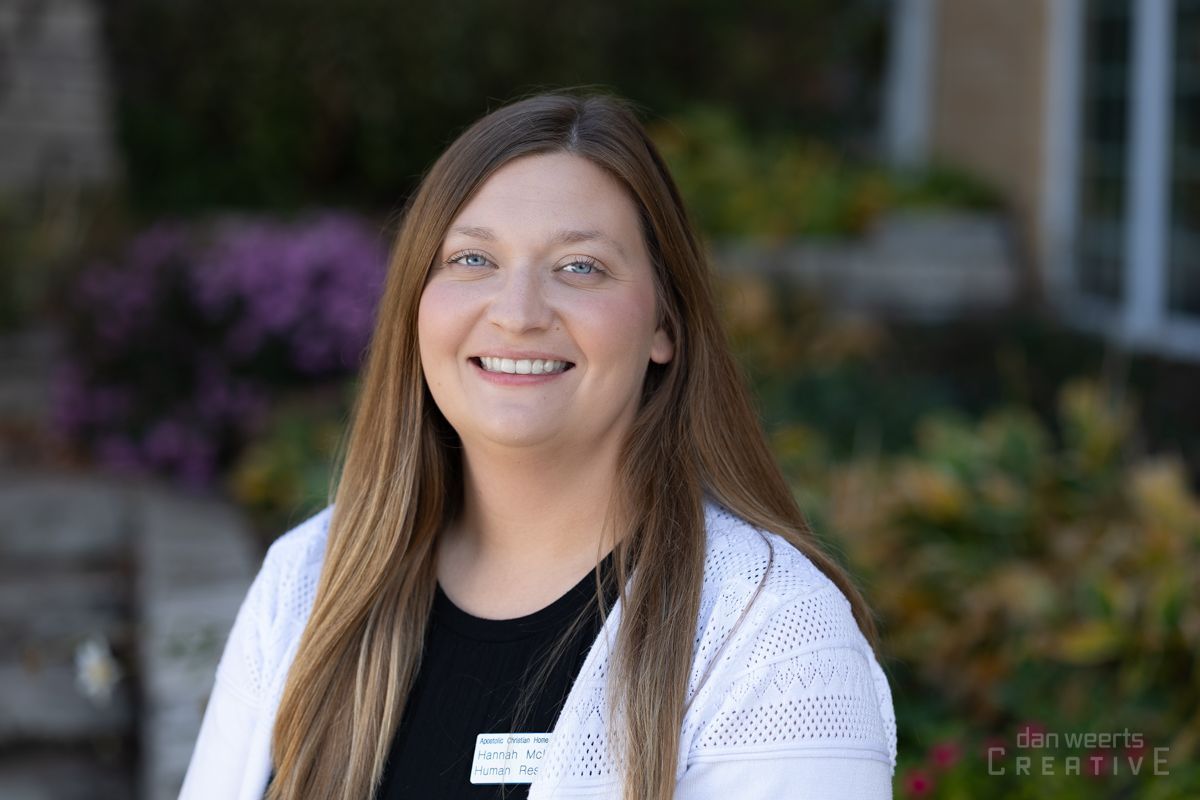 A woman wearing a white sweater and a black shirt is smiling for the camera.