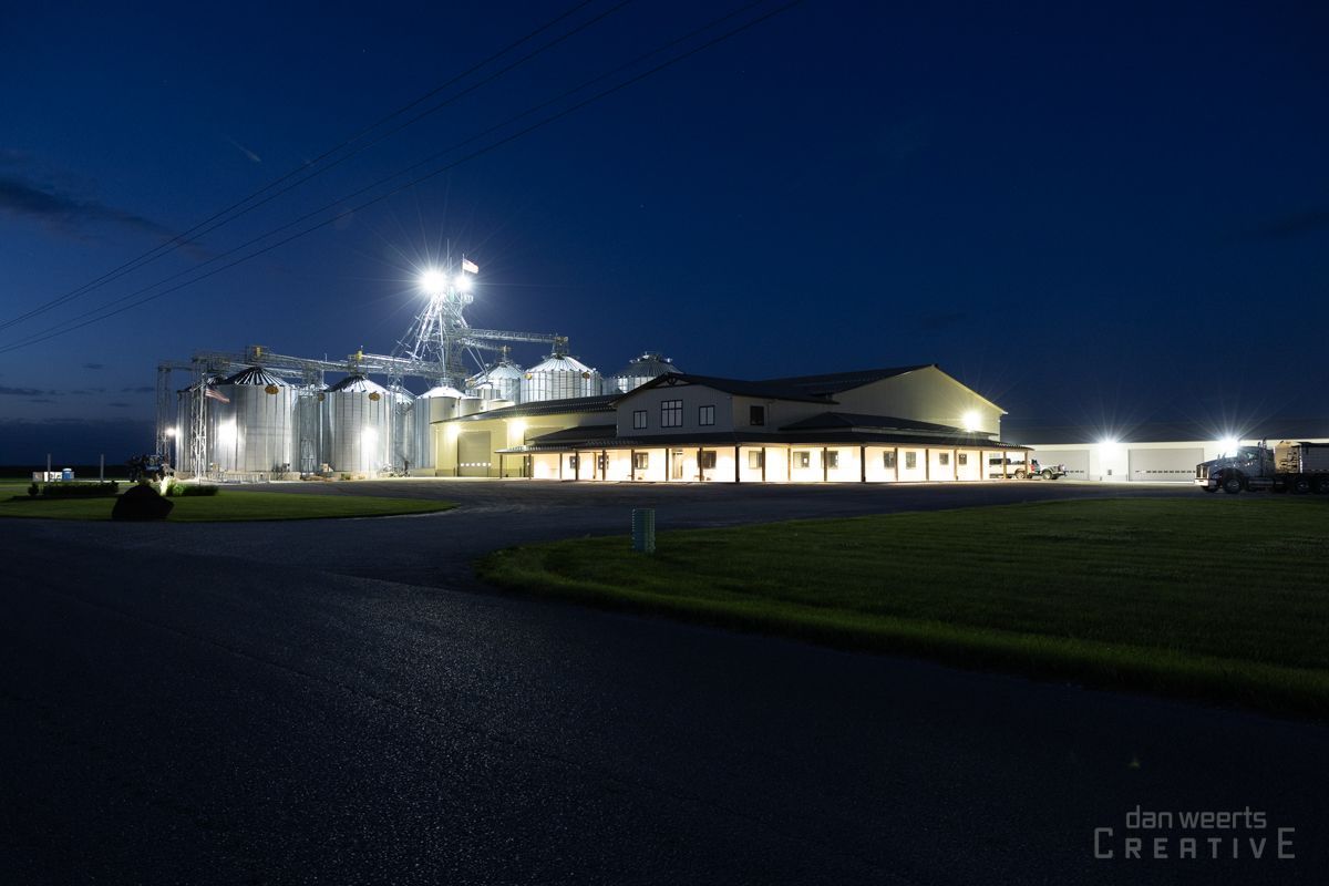 A large building with a lot of silos is lit up at night.
