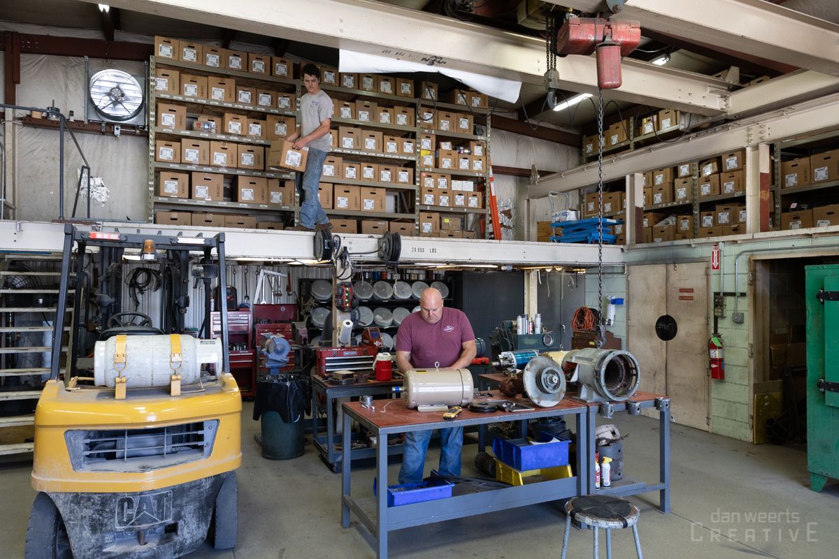 A man is sitting at a table in a factory working on a machine.