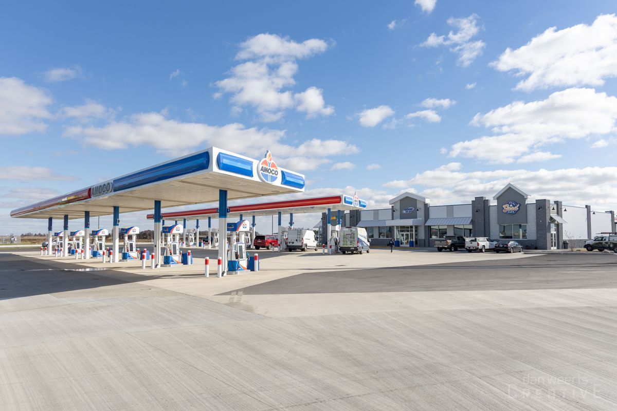 A gas station with a lot of cars parked in front of it on a sunny day.