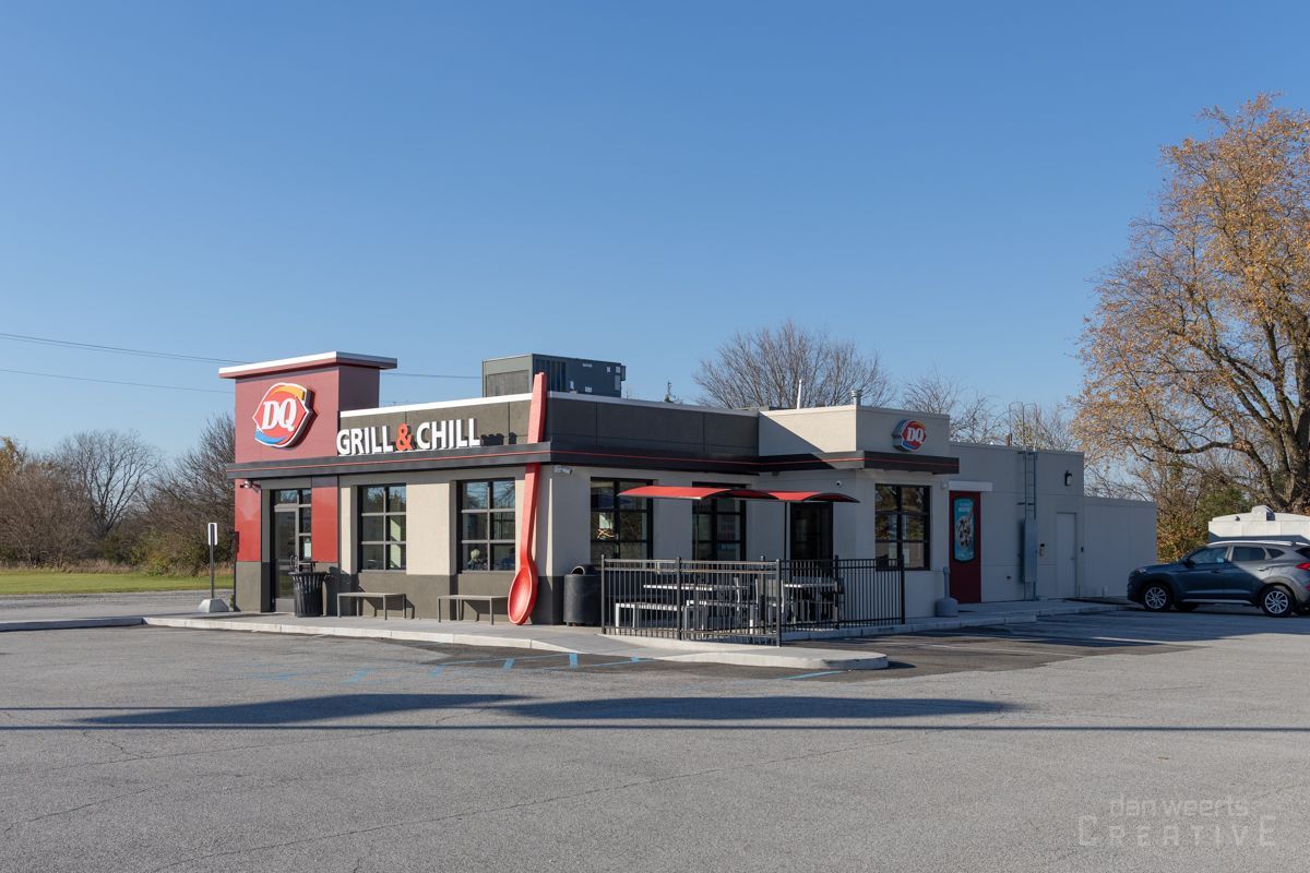 A fast food restaurant with cars parked in front of it.