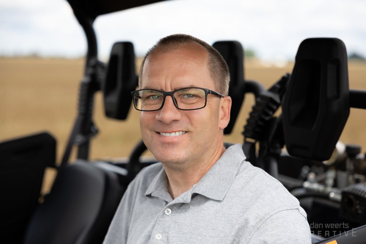 A man wearing glasses is sitting in the back seat of a vehicle.