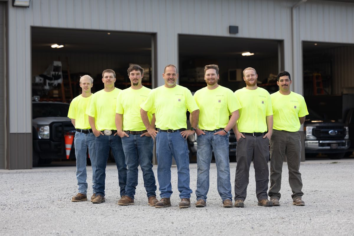 A group of men are posing for a picture in front of a garage.