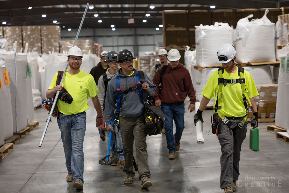 A group of construction workers are walking through a warehouse.