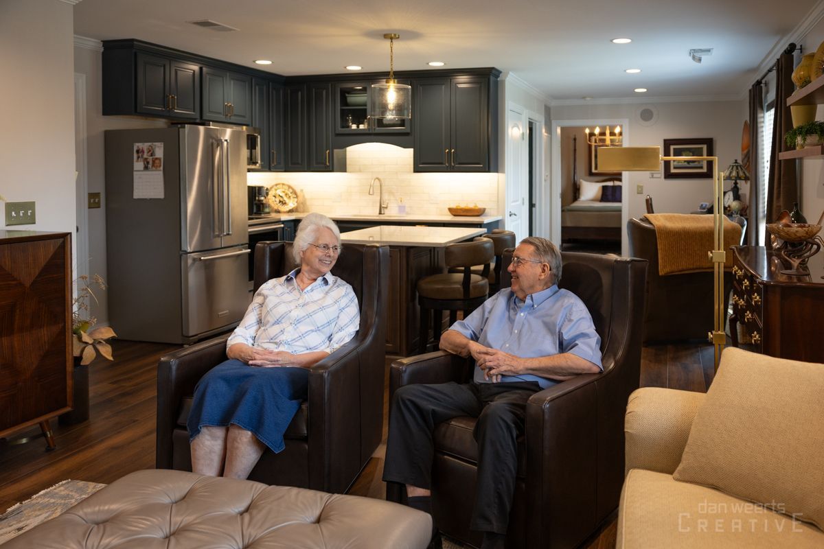 A man and a woman are sitting in chairs in a living room.
