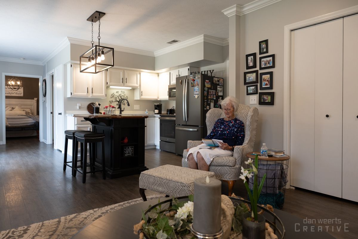 An elderly woman is sitting in a chair in a living room.