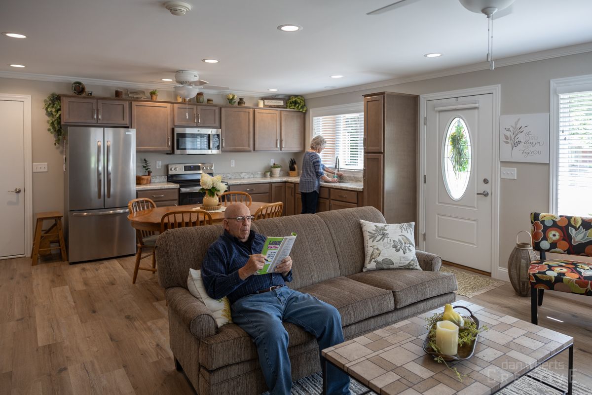 A man is sitting on a couch in a living room reading a book.