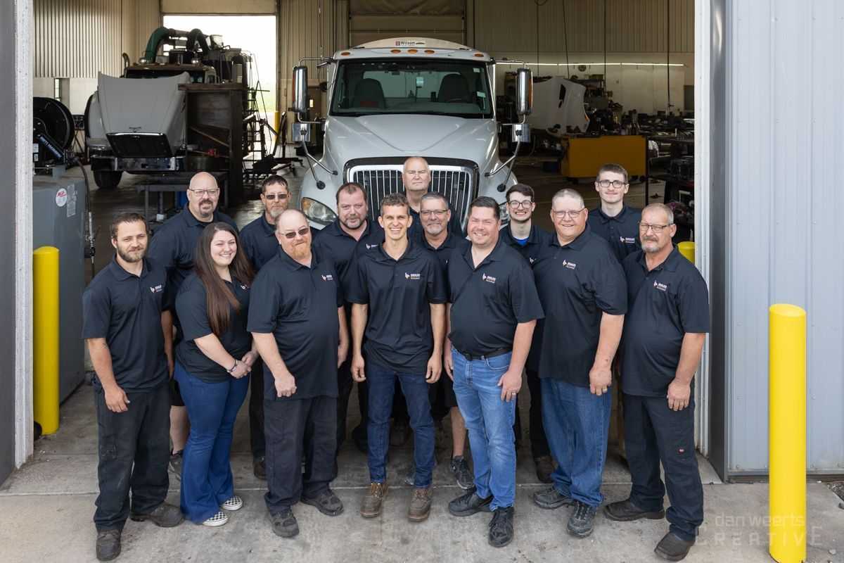 A group of people are posing for a picture in front of a truck.
