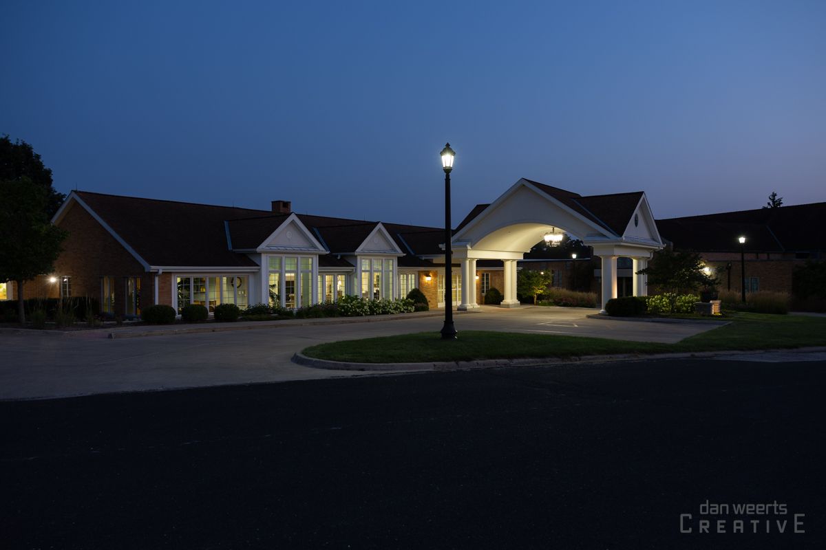 A large house is lit up at night with a street light in front of it.