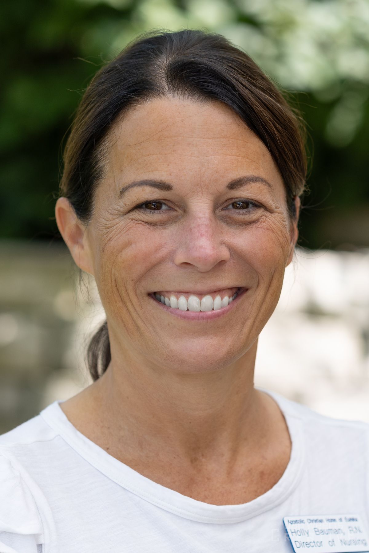 A woman in a white shirt is smiling for the camera.