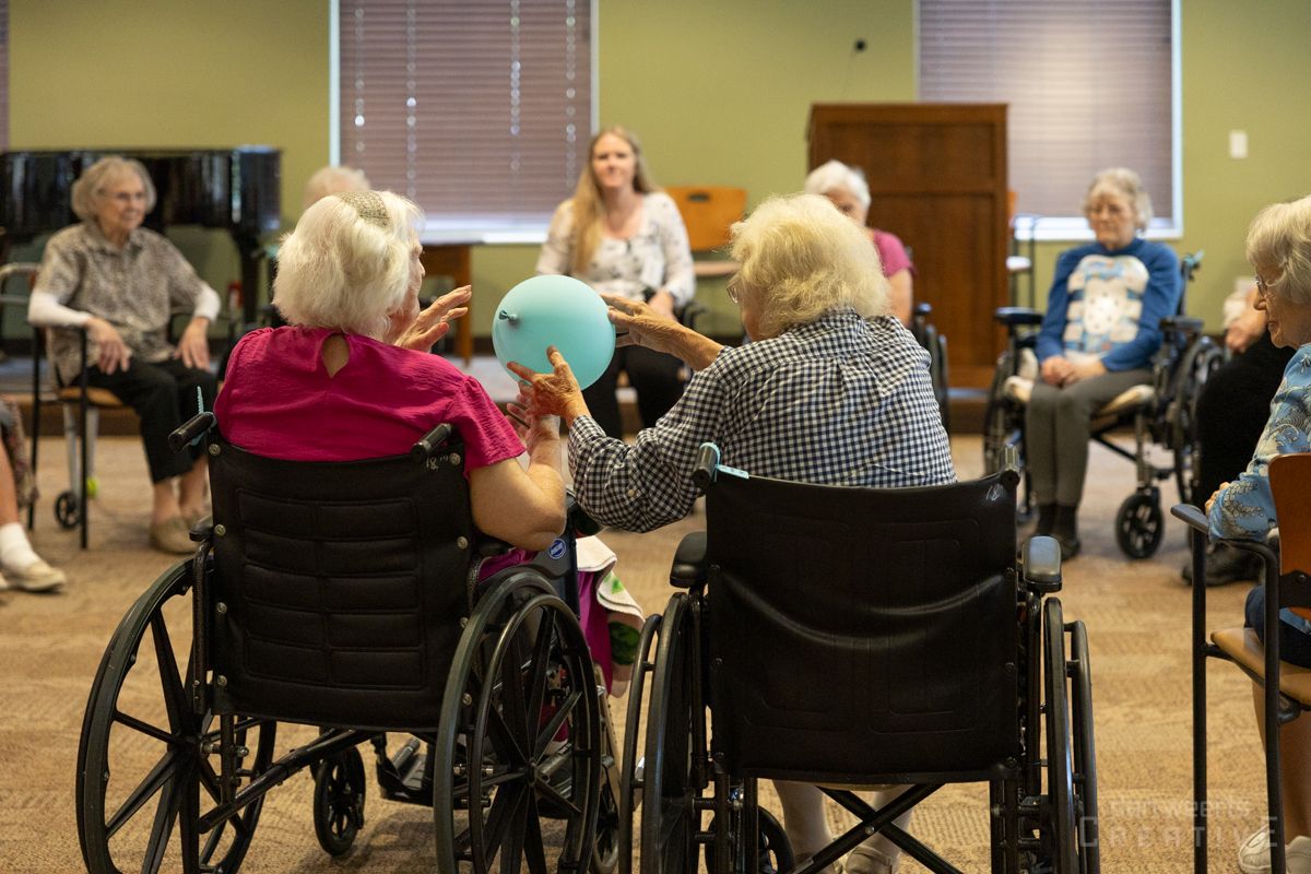 A group of elderly people in wheelchairs are playing with a ball.