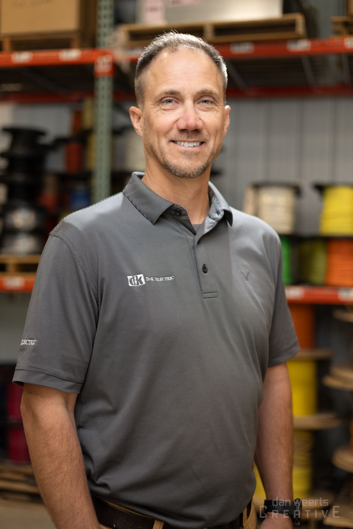 A man in a gray shirt is standing in a warehouse.