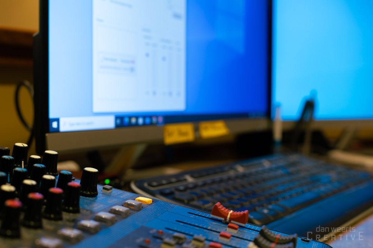 A computer monitor is sitting next to a keyboard and a mixer.
