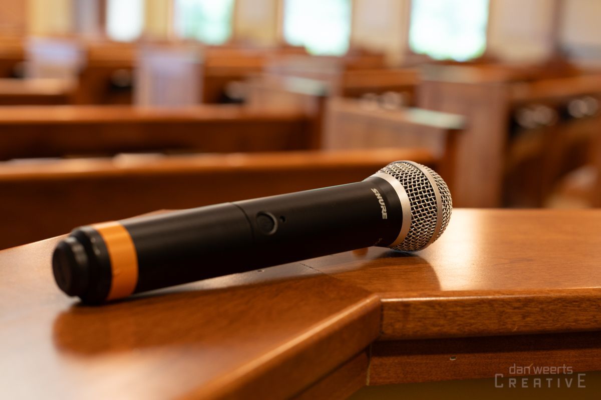 A microphone is sitting on a wooden table in a church