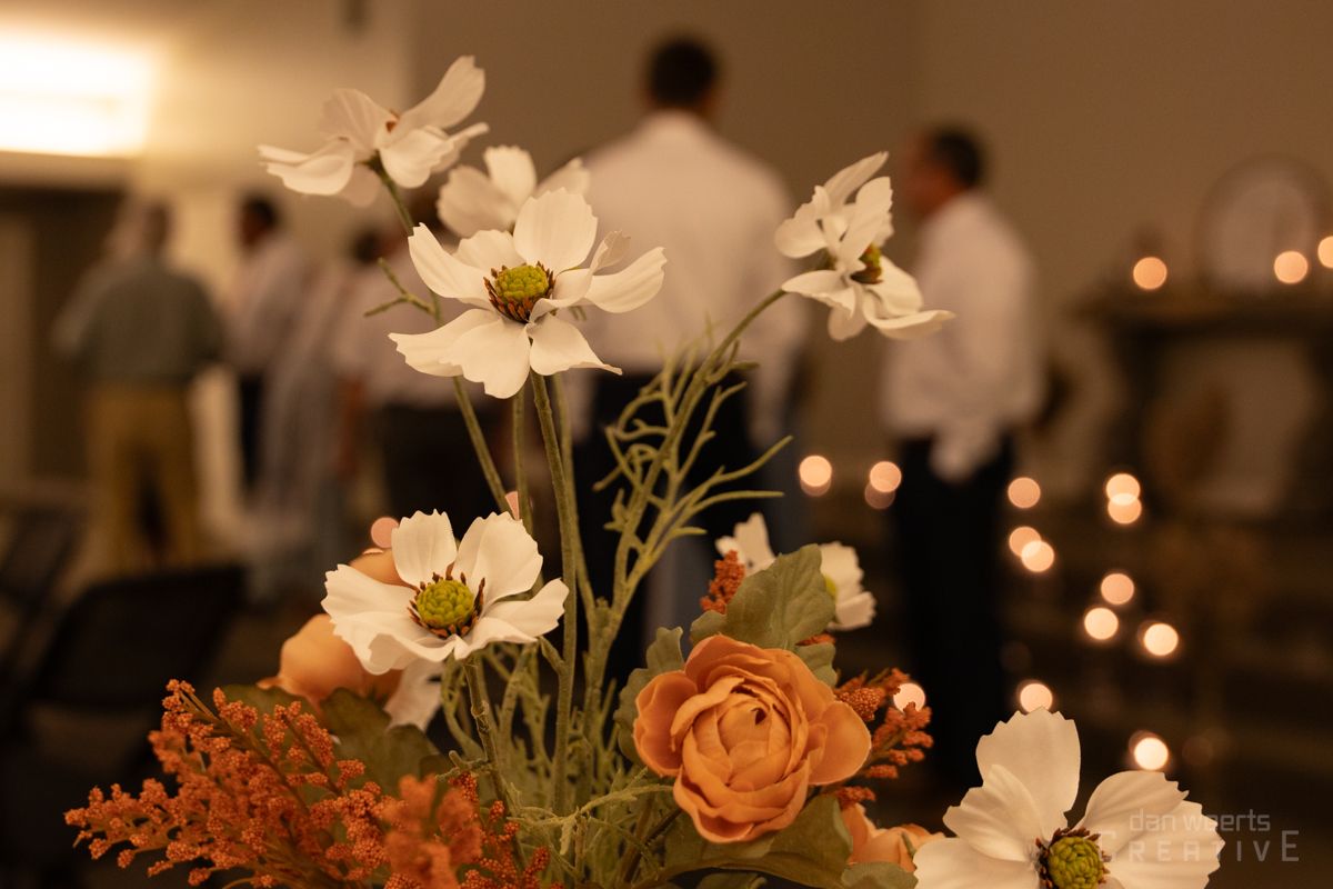 A bunch of flowers in a vase with candles in the background.