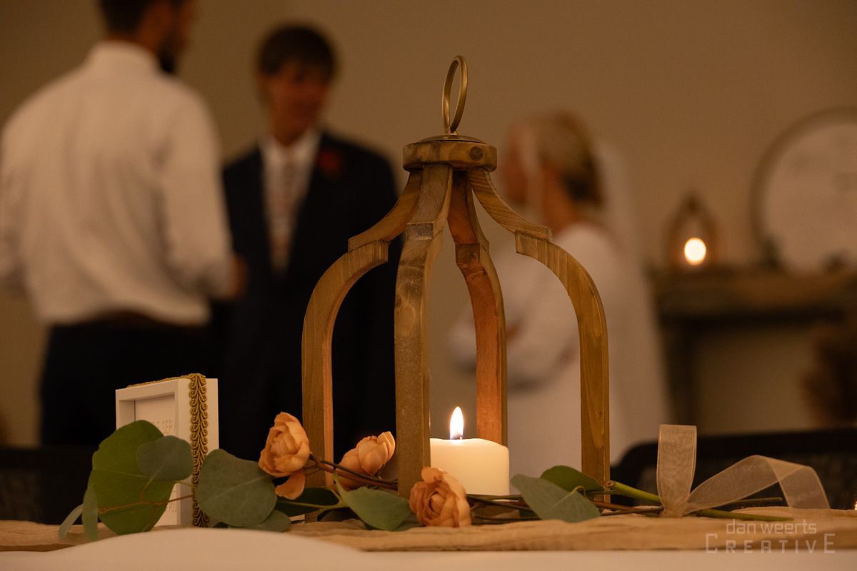 A candle is lit in a wooden lantern on a table.
