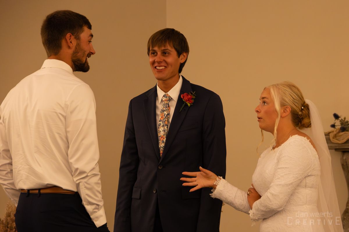 A bride and groom are standing next to each other in a room talking to each other.