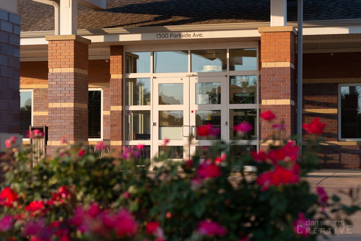 A brick building with a glass door and flowers in front of it