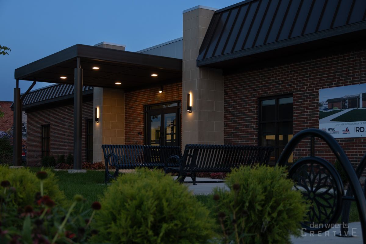 A brick building with a metal roof and a bench in front of it.
